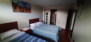 a hotel room with two beds and a mirror at HOSTAL SAMAYWASI in Huancayo