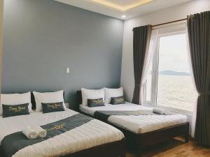 a bedroom with two beds and a window with the ocean at DANA BEACH Motel in Danang