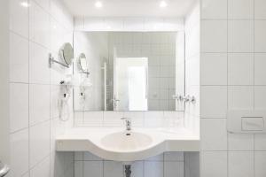 a white bathroom with a sink and a mirror at Aparthotel Kühlungsborn, Villa am Konzertgarten in Kühlungsborn