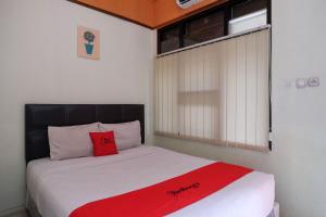 a bedroom with a bed with a red blanket on it at RedDoorz near Lotte Mart Maguwoharjo Yogyakarta in Yogyakarta