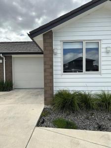 a white house with a garage and a driveway at Cosy Self Contained 2 Bedroom Townhouse in Hamilton