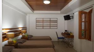 a room with two beds and a desk and a window at Hotel Casa del Arbol in San Pedro Sula