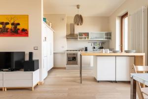 米蘭的住宿－Schiavoni Flexyrent WiFi，厨房配有白色橱柜和一张桌子及一台电视机