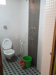 baño con aseo y cubo verde en Nisarga Homestay, en Gokarna