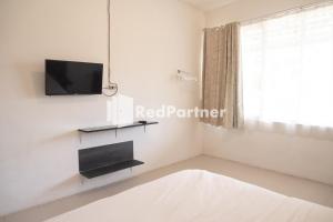 Habitación blanca con TV y cama en Homestay C9 Exclusive Kaliurang Yogyakarta Mitra RedDoorz, en Yogyakarta