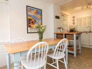 cocina con mesa de madera y sillas blancas en Crab Cottage, en Ilfracombe