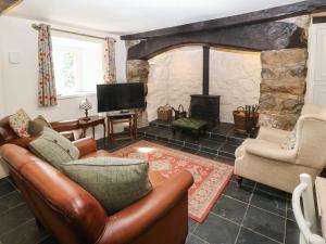 a living room with leather furniture and a fireplace at Y Bwthyn Ty Du in Llannor