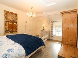 a bedroom with a bed and a dresser and a chandelier at Y Bwthyn Ty Du in Llannor