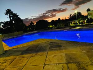 a blue swimming pool with a sunset in the background at 2 Private Bedrooms - homestay in Summerstrand