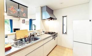 a white kitchen with a sink and a refrigerator at 我が家inOKINAWA 私の家in沖縄 in Onna