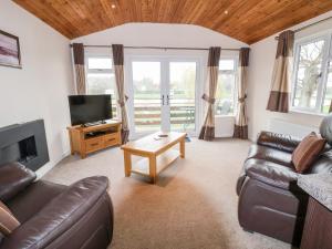 a living room with a couch and a television at Oak Lodge in Hadnall