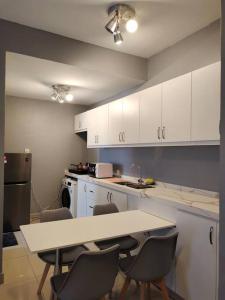 a kitchen with white cabinets and a table and chairs at Urban360 studio lovely stay with Wi-Fi in Batu Caves