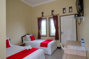 a hotel room with two beds and a table at RedDoorz Syariah near Taman Rekreasi Kalianget Wonosobo in Kalianget