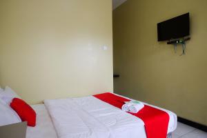 a bedroom with a bed with a red and white blanket at RedDoorz Syariah near Taman Rekreasi Kalianget Wonosobo in Kalianget