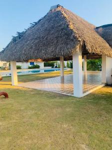 a hut with a grass roof and a pool at Enjoy a beautiful beach house in Panamá in Río Hato