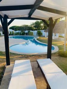 dois bancos brancos debaixo de um guarda-sol perto de uma piscina em Enjoy a beautiful beach house in Panamá em Río Hato