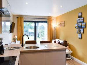 a kitchen with a sink and a living room at Stone Cottage in Wingerworth