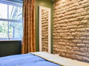ein Schlafzimmer mit einer Ziegelwand, einem Bett und einem Fenster in der Unterkunft Stone Cottage in Wingerworth