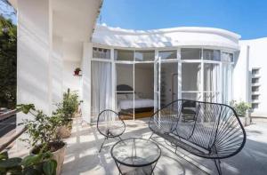eine Terrasse mit 2 Stühlen und einem Bett in einem Haus in der Unterkunft Casa Pani in Mexiko-Stadt