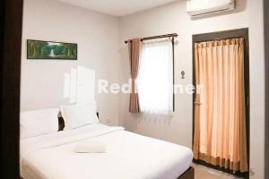 ein Schlafzimmer mit einem weißen Bett und einem Fenster in der Unterkunft Panorama İnn Residence Batu Mitra RedDoorz in Batu