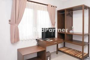 Zimmer mit einem Schreibtisch, einem TV und einem Fenster in der Unterkunft Panorama İnn Residence Batu Mitra RedDoorz in Batu
