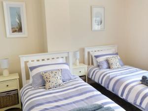 twee bedden in een slaapkamer met blauwe en witte strepen bij Wheelhouse 21 in Amble