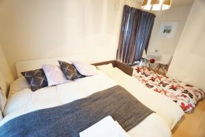 um quarto com uma grande cama branca com almofadas em 横浜ザ・アパートメント em Yokohama