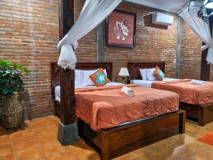 a bedroom with two beds and a brick wall at Ndalem Suryo Saptono Guest House in Yogyakarta