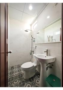 a white bathroom with a toilet and a sink at Quan Quan Hotel in Danang