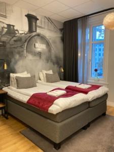 a bedroom with a large bed with a train on the wall at Livin Station Hotel in Örebro