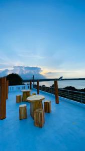 un grupo de mesas y bancos en una terraza con vistas al agua en KPN Trinco Holiday Resort en Trincomalee