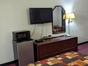 a hotel room with a bed and a dresser with a television at Luxury inn in Mustang