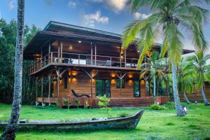 a wooden house with palm trees in front of it at Eco-Lodge Bocas Coral Reef - Over water villa & birds house in Botabite