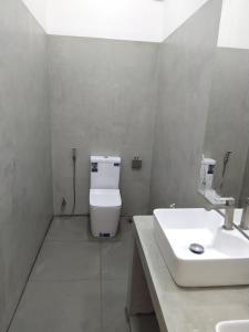 a bathroom with a white toilet and a sink at Savendro in Hikkaduwa