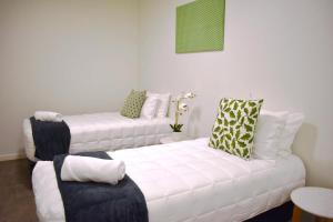 uma sala de estar com 2 sofás brancos com almofadas em U Suites on Webb em Wellington