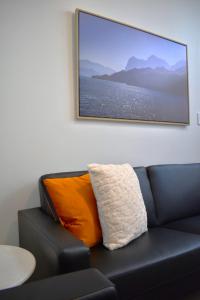 a black couch with an orange pillow sitting under a painting at U Suites on Webb in Wellington