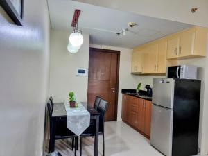 Il comprend une petite cuisine équipée d'une table et d'un réfrigérateur. dans l'établissement One Palm Tree Villas Condo Across NAIA Terminal 3, à Manille