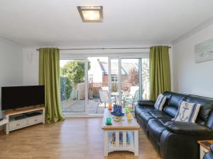ein Wohnzimmer mit einem schwarzen Ledersofa und einem TV in der Unterkunft Sea Pebbles in Weymouth