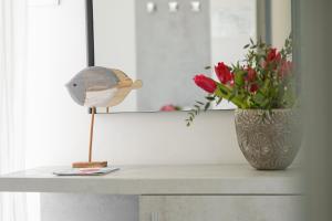 uma mesa com uma estatueta de pássaro e um vaso de flores em Hotel Mon Pays em Rimini