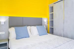 uma cama com duas almofadas azuis e uma parede amarela em Hotel Mon Pays em Rimini