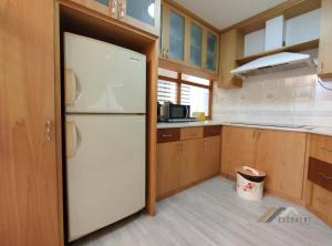 uma cozinha com um frigorífico branco e armários de madeira em Imperial Suites by Evernent em Miri