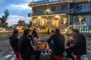 a group of people sitting around a fire in front of a house at The Trippy Tribe Extended in Bīr