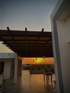 a patio with a table and a sunset in the background at Jabal almumsi in Rasīs