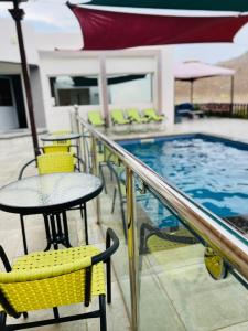 a patio with a table and chairs next to a swimming pool at Jabal almumsi in Rasīs