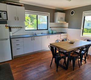 a kitchen with white cabinets and a table with chairs at Shellharbour Holiday Village in Barrack Point