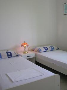 two beds in a room with a lamp on a night stand at Apartments Sugar in Mandre