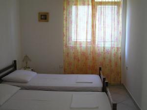 a bedroom with two beds and a window with curtains at Apartments Sugar in Mandre +18 photos