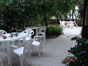 a patio with white tables and chairs and trees at Apartments Sugar in Mandre