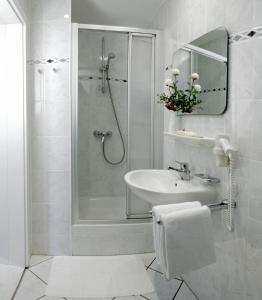 a white bathroom with a shower and a sink at Villa Neptun in Heringsdorf