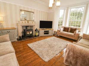 a living room with a television and a fireplace at Penholm in Penmaen-mawr